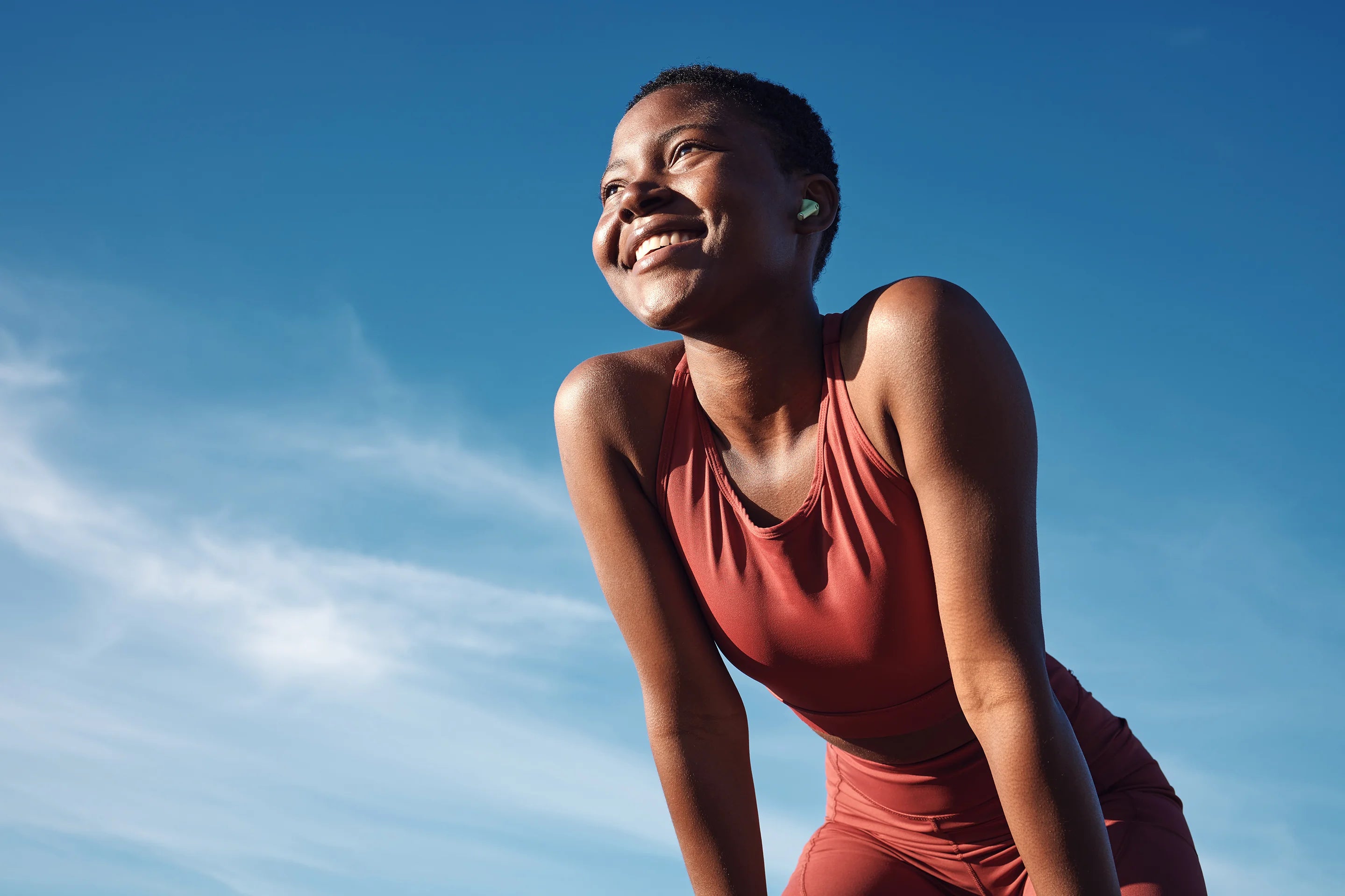 Woman in red athletic outfit against a blue sky