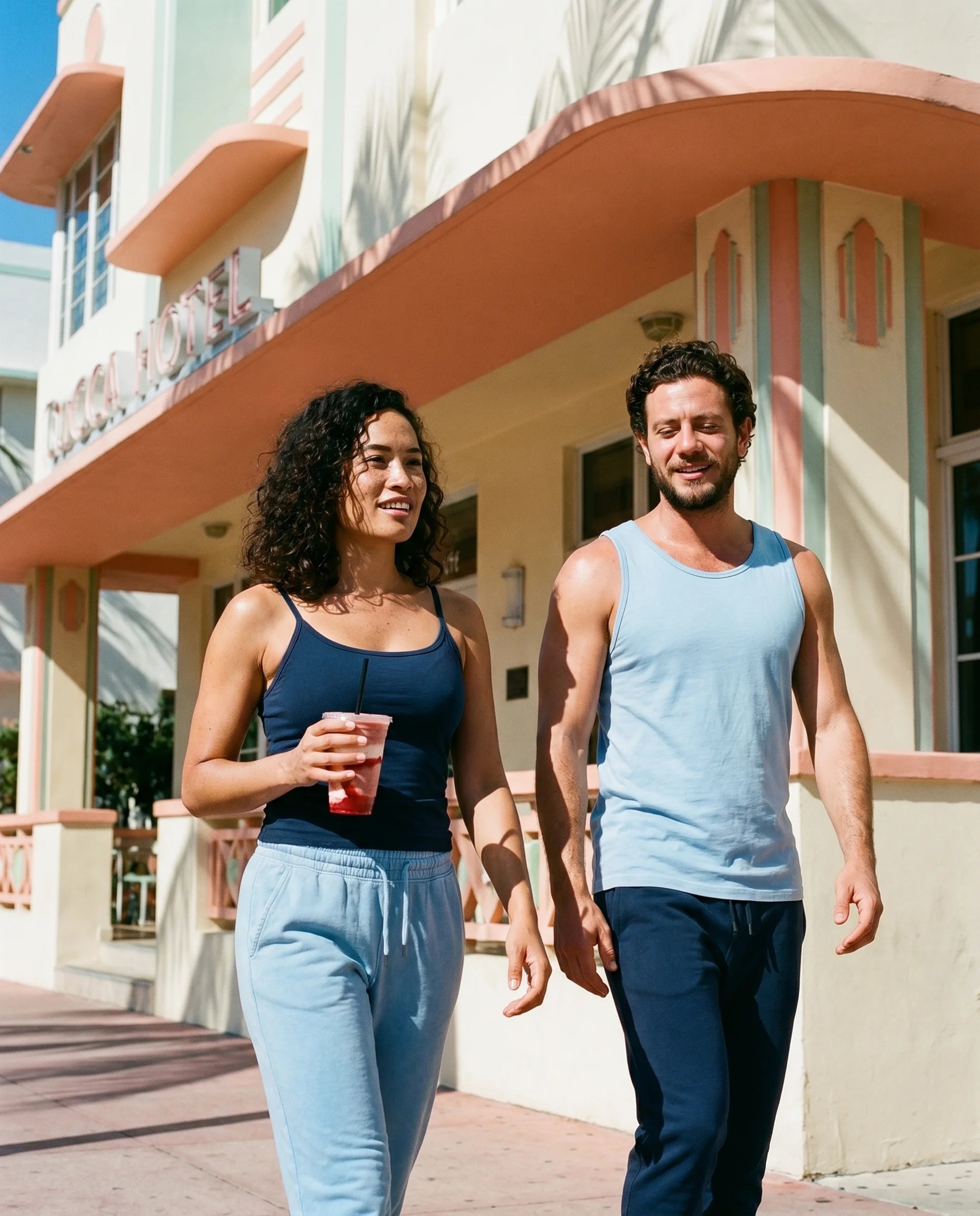 Two people walking together in front of a colorful building.