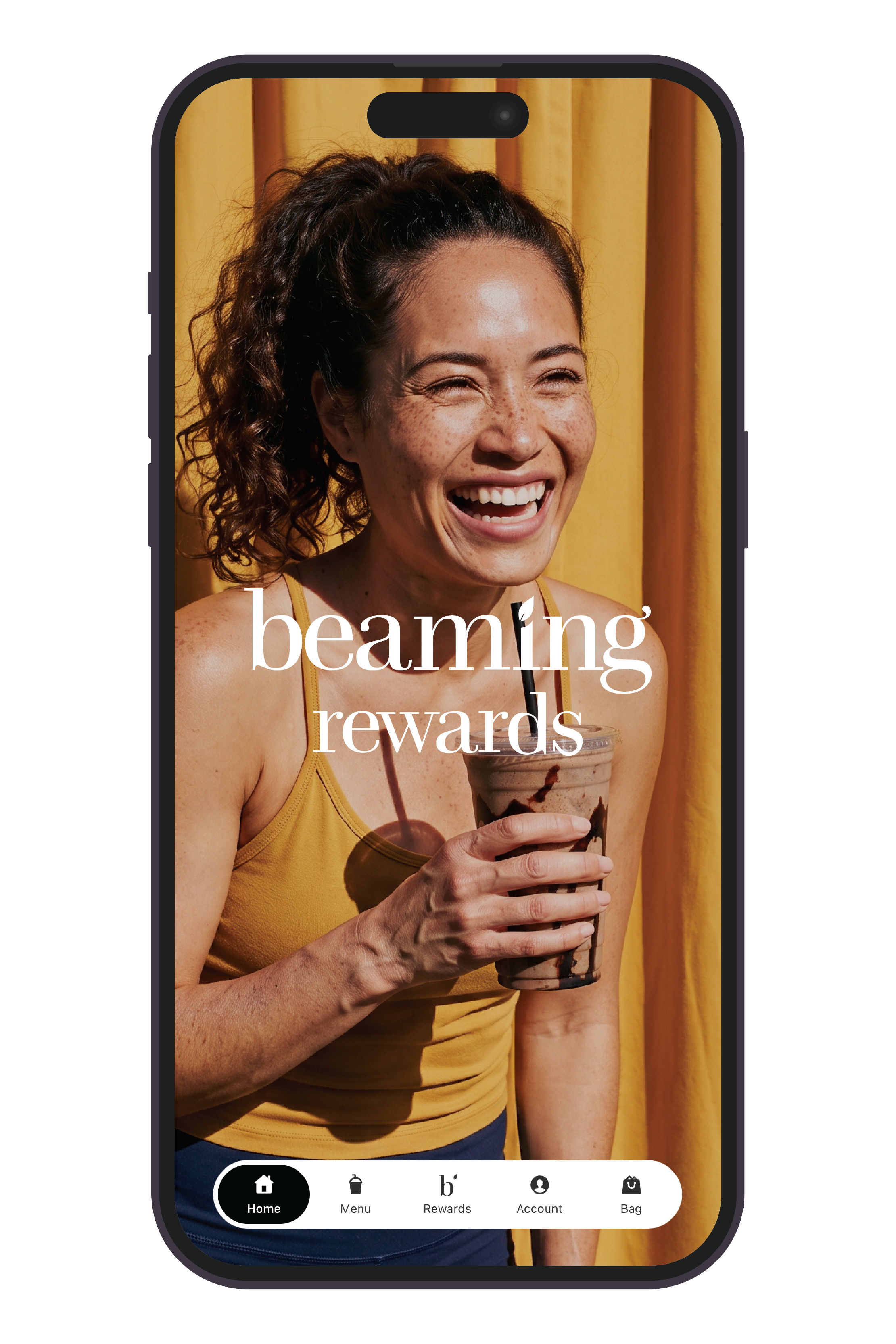 A black smartphone mockup on a white background, displaying a rewards app screen with a smiling woman in a yellow top holding an iced coffee in front of yellow curtains. The screen text reads 'beaming rewards' with navigation icons along the bottom.